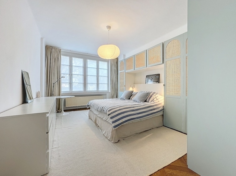 Chambre moderne lumineuse avec lit gris, décoration épurée et ambiance relaxante.