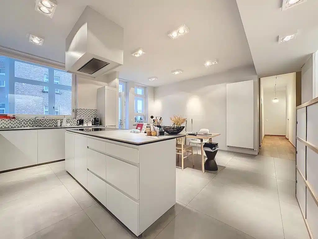 Cuisine moderne blanche, lumineuse, minimaliste avec îlot central, design épuré et éclairage naturel.