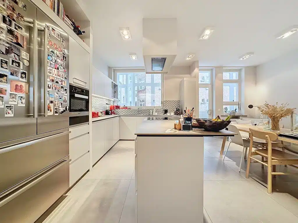 Cuisine moderne minimaliste avec îlot, lumière naturelle, apparence épurée et appareils inox intégrés.