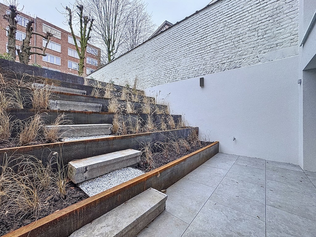 Escalier en béton pendant urbain, mêlant nature sauvage et design moderne sur un fond blanc.