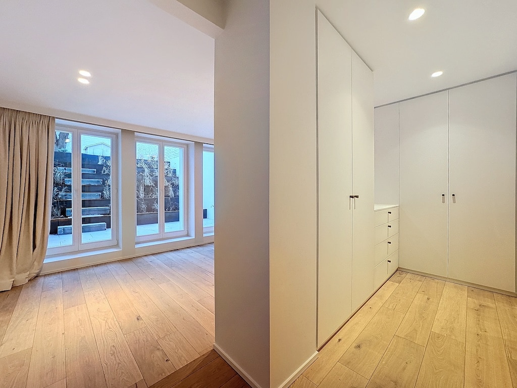 Espace moderne minimaliste avec lumière naturelle, murs pastel, sol en bois, et dressing intégré blanc