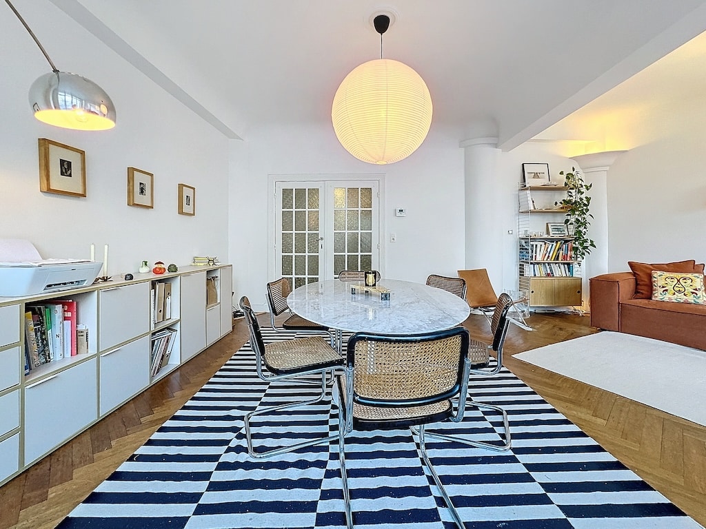 Salle à manger scandinave élégante avec table ovale, chaises en osier et espace cosy avec plantes