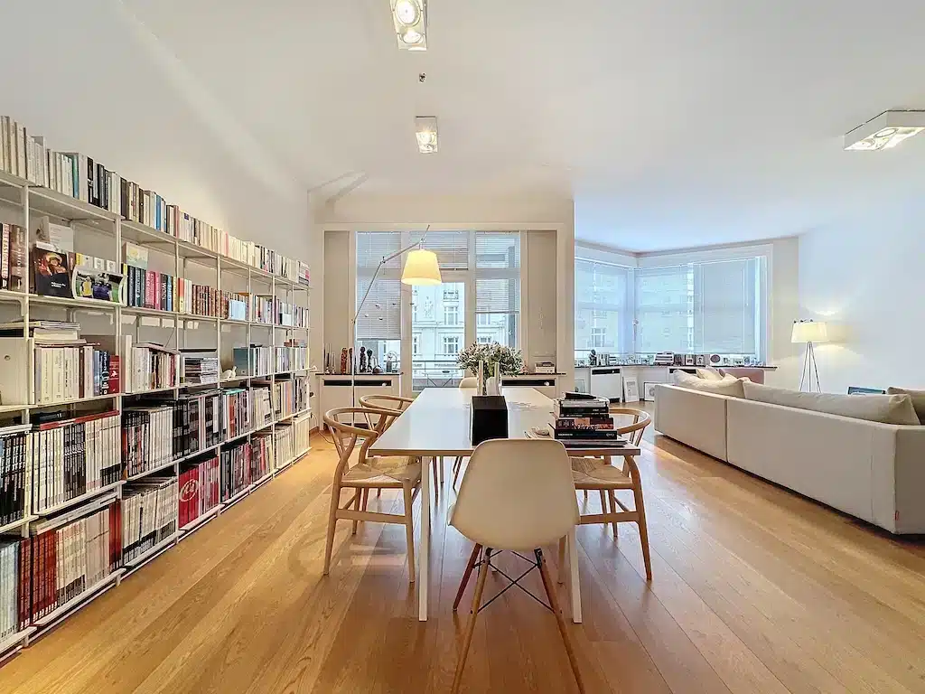Salon moderne lumineux avec meubles épurés, grande bibliothèque et ambiance chaleureuse naturelle.