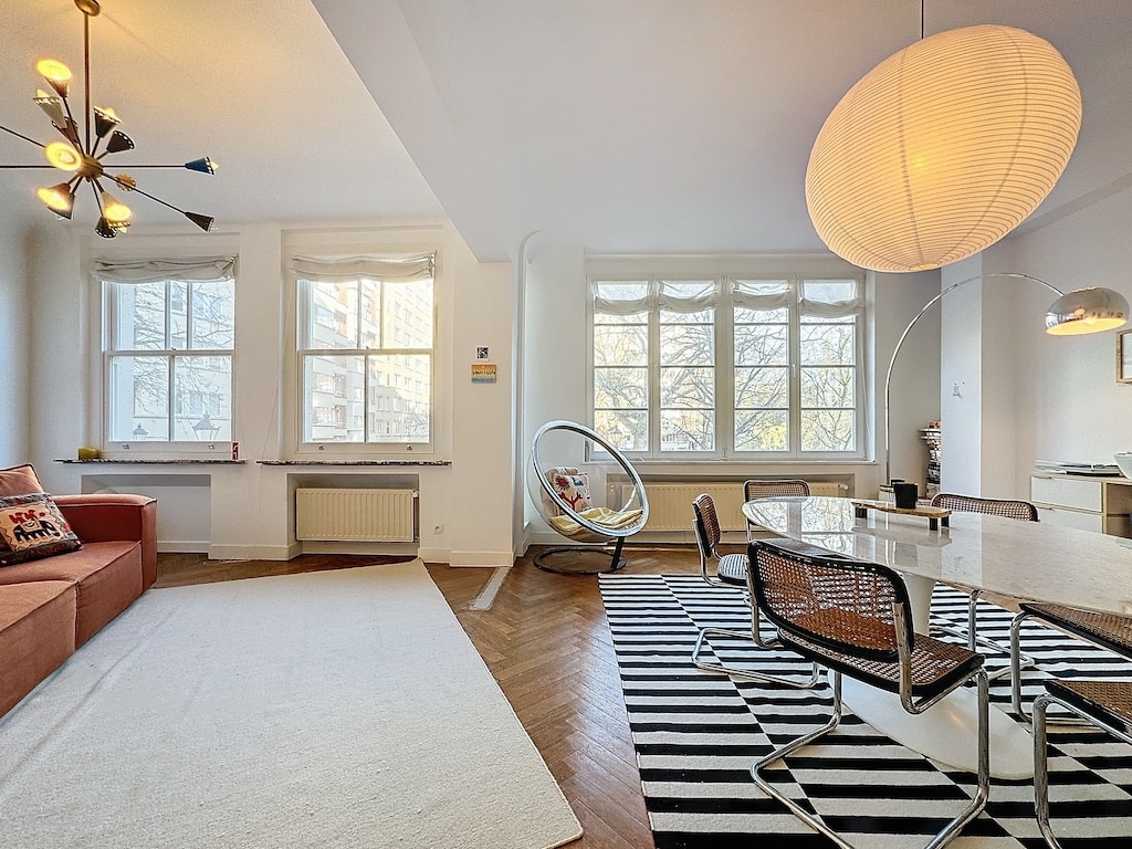 Salon moderne lumineux avec canapé orange, tapis noir et blanc, espace détente élégant.