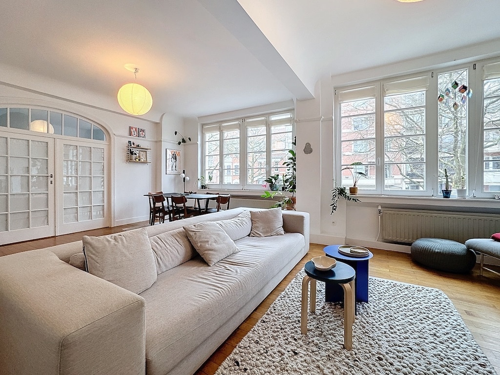 Salon lumineux avec canapé, tapis, plantes vertes et décoration moderne pour la détente.