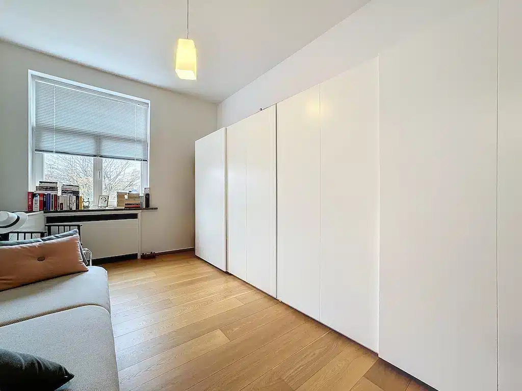Salon moderne minimaliste avec lumière naturelle, mobilier épuré, façades blanches et ambiance chaleureuse.