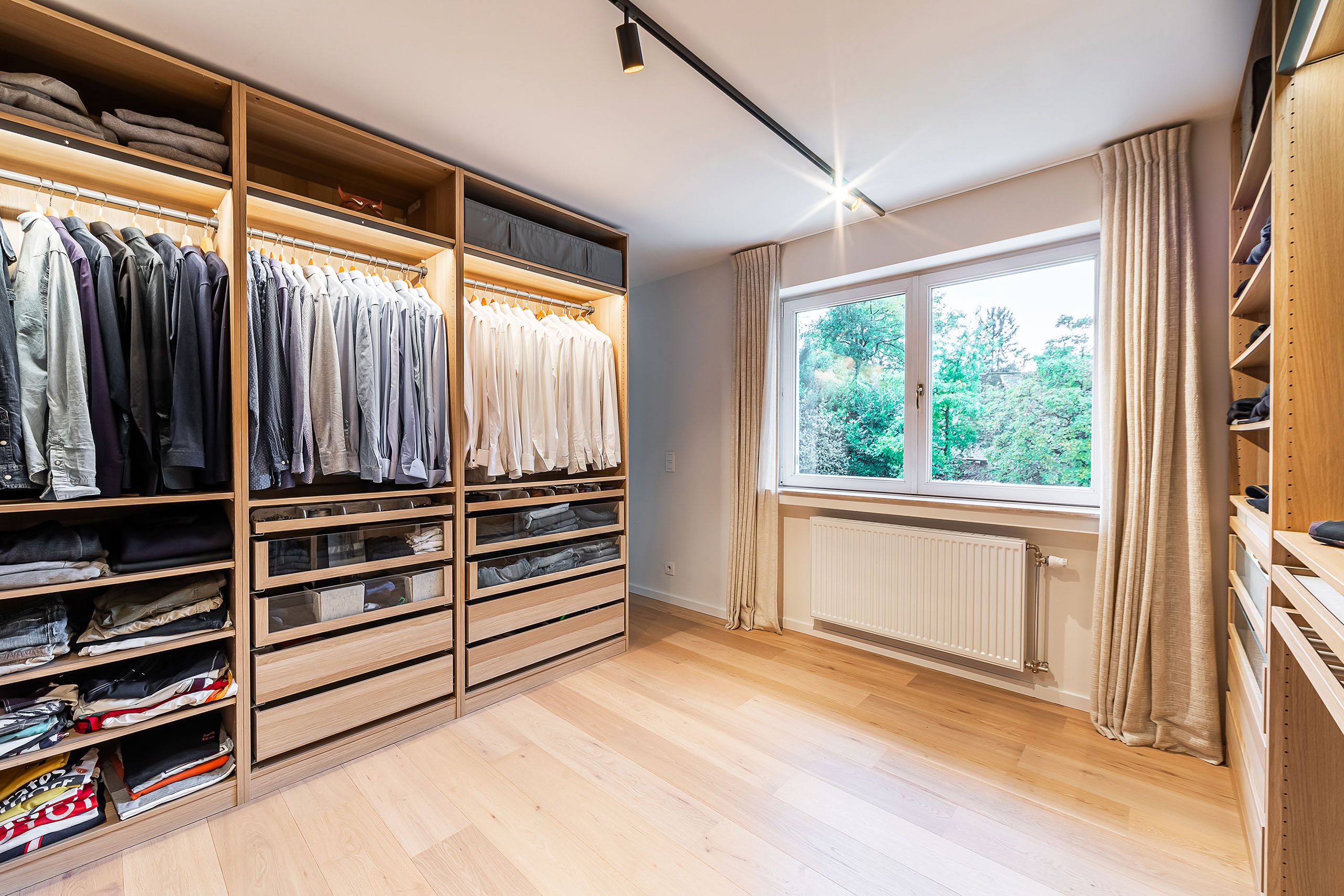 Dressing moderne en bois chaleureux avec rangement organisé et lumière naturelle.
