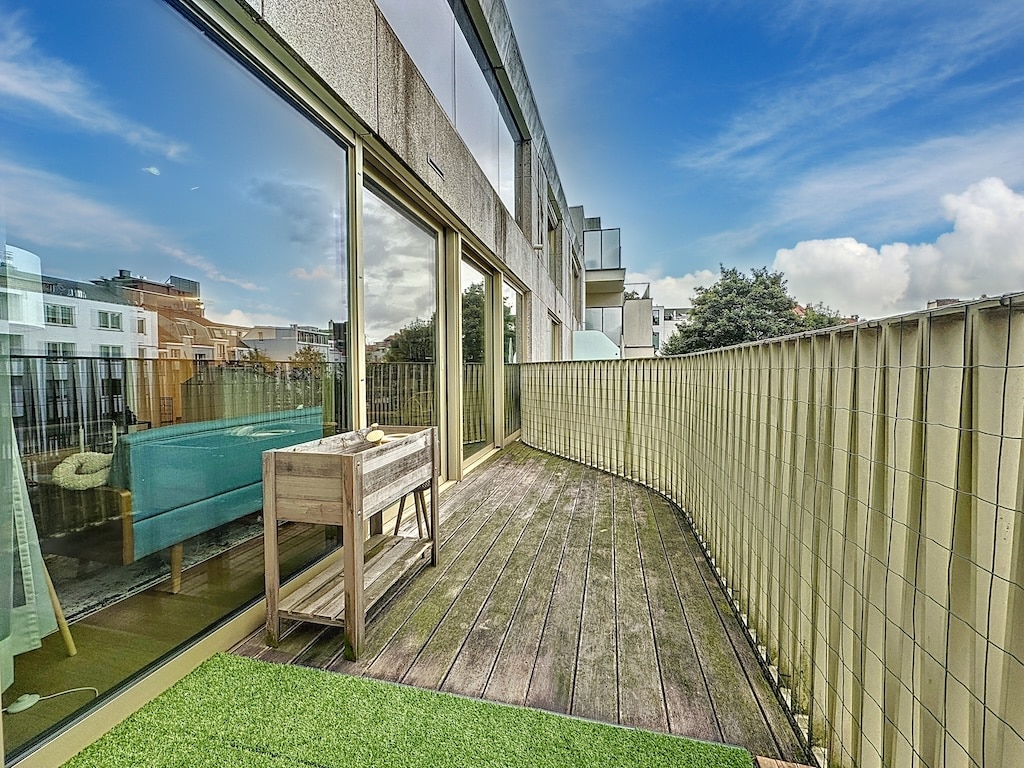 Balcon moderne en bois avec vue urbaine, terrasse lumineuse, plantes vertes et espace détente.