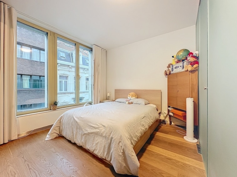 Chambre moderne lumineuse avec lit en bois, fenêtres généreuses et espace de rangement ludique.