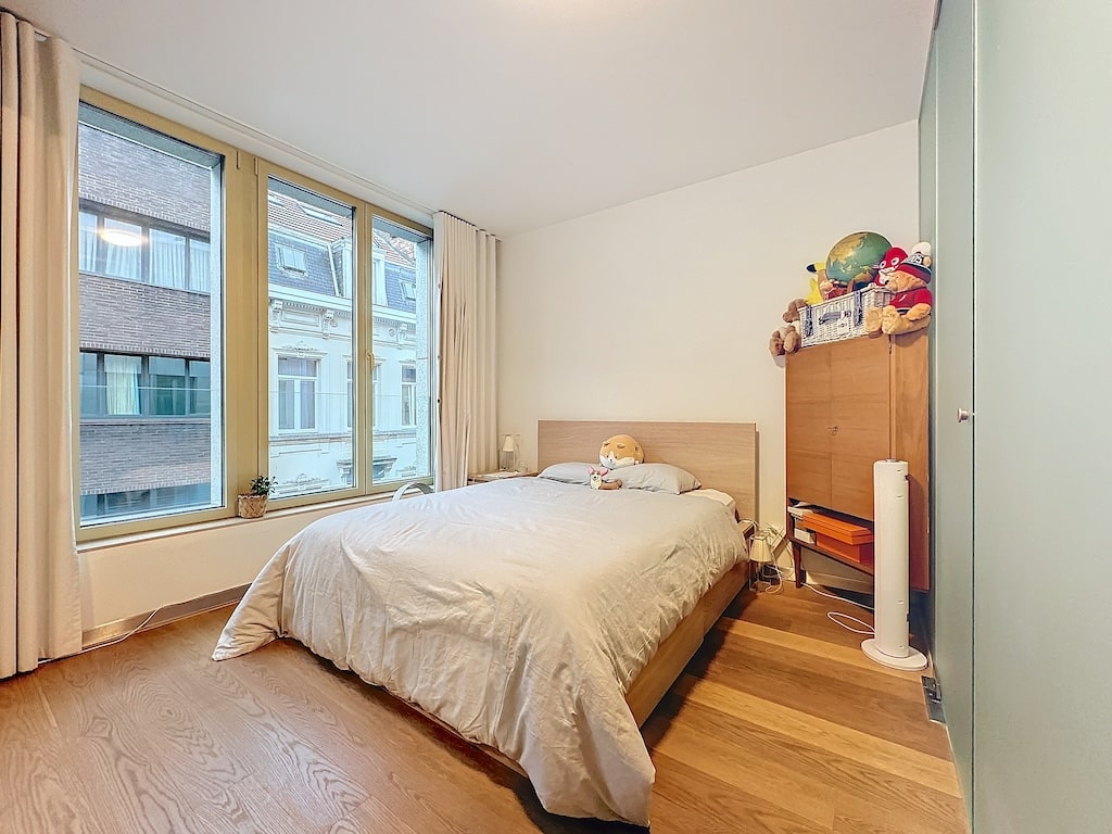 Chambre moderne lumineuse avec lit en bois, fenêtres généreuses et espace de rangement ludique.