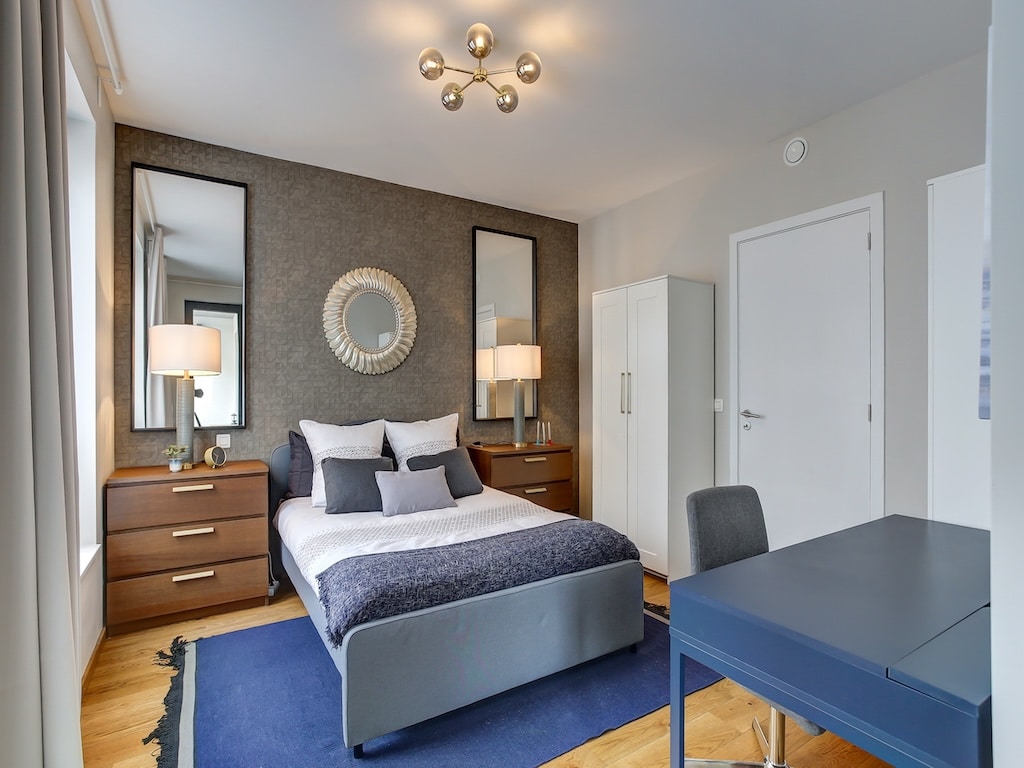 Chambre moderne élégante avec lit blanc, espace de travail, miroirs et ambiance chaleureuse.