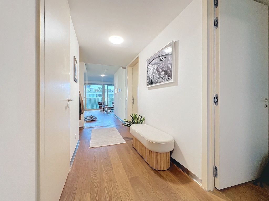 Couloir lumineux et minimaliste avec parquet clair, décoration moderne et vue ouverte sur le salon.