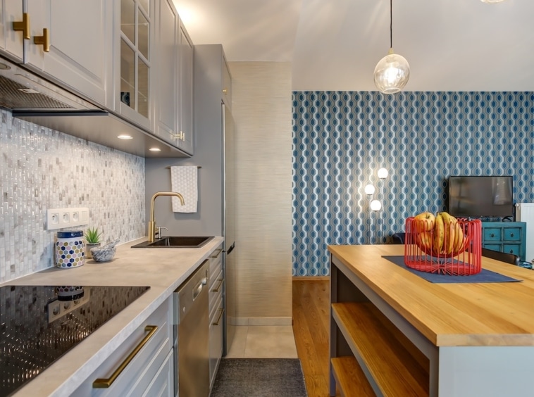 Cuisine moderne avec îlot en bois, éclairage chaleureux, murs bleus graphiques et espace convivial.