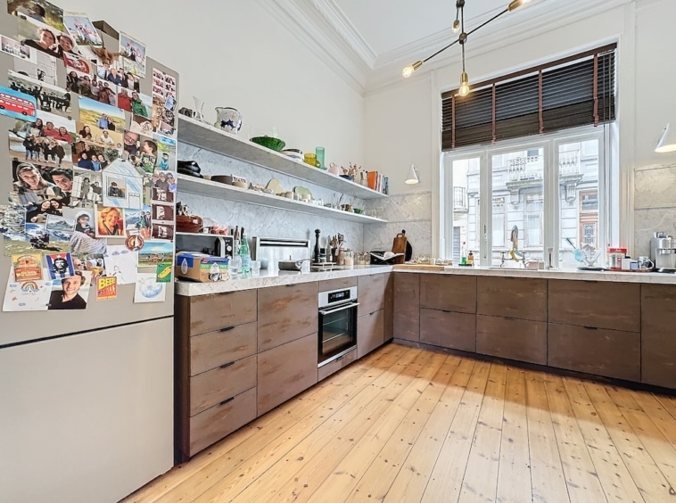 Cuisine moderne chaleureuse avec rangements ouverts, mobilier en bois foncé et lumière naturelle.