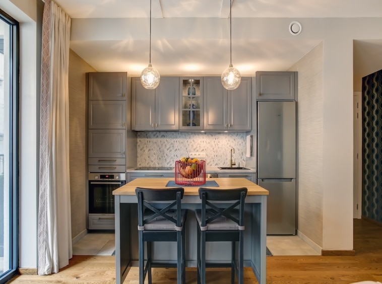 Cuisine moderne lumineuse avec îlot convivial, placards gris, éclairage suspendu et design élégant.