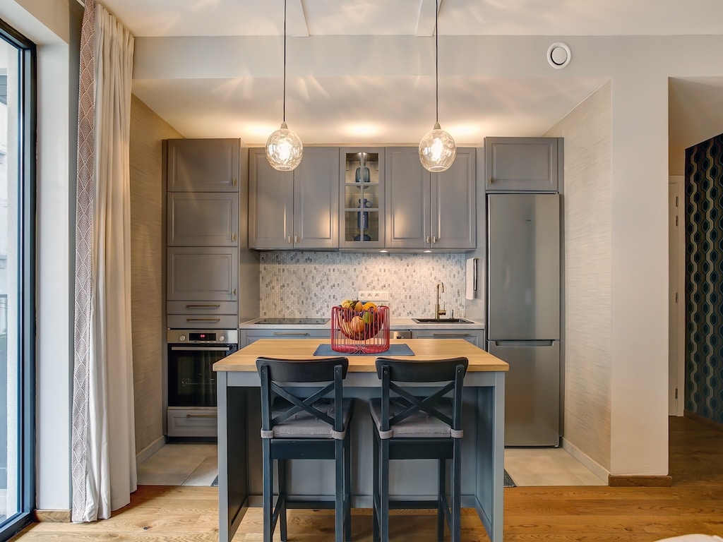Cuisine moderne lumineuse avec îlot convivial, placards gris, éclairage suspendu et design élégant.