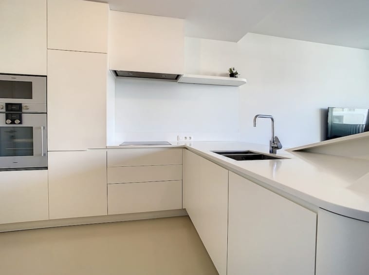 Cuisine moderne blanche, lumineuse, minimaliste, plans intégrés, appareils encastrés, design épuré.