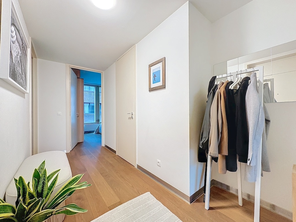 Entrée minimaliste chaleureuse avec murs blancs, bois clair, décoration élégante et lumière naturelle.
