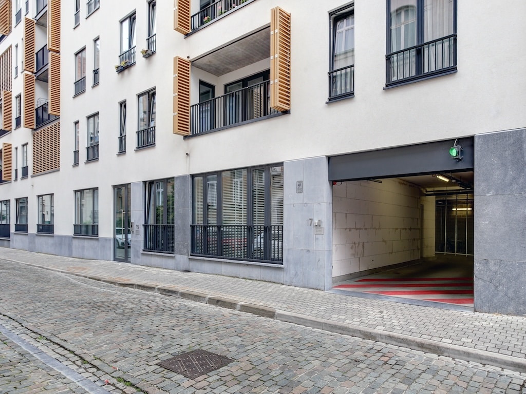 Rue urbaine moderne avec parking, façade minimaliste, architecture contemporaine et ambiance résidentielle.