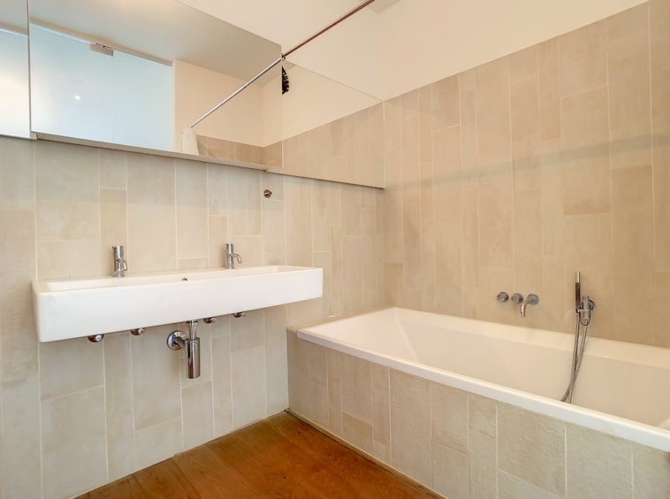 Salon de bain moderne, minimaliste, neutre, avec lavabo, baignoire, miroir, design épuré.