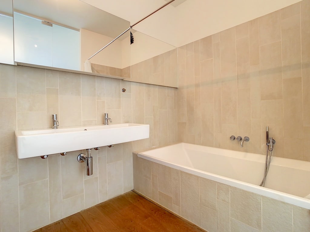 Salon de bain moderne, minimaliste, neutre, avec lavabo, baignoire, miroir, design épuré.