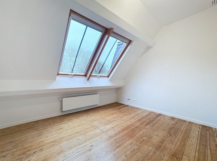 Espace lumineux minimaliste avec grandes fenêtres triangulaires et vue sur la nature.