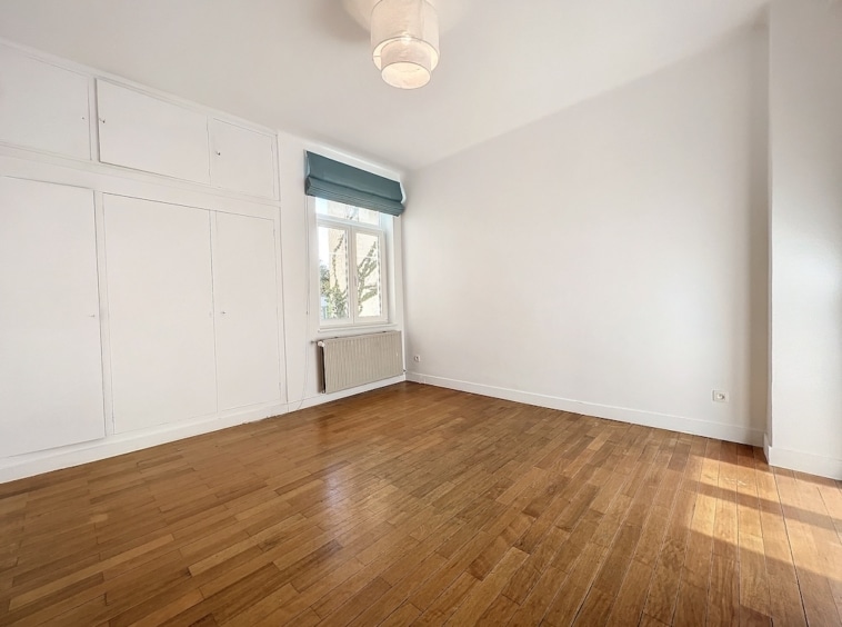 Salon lumineux minimaliste avec fenêtre sur la verdure et rangements intégrés modernes.