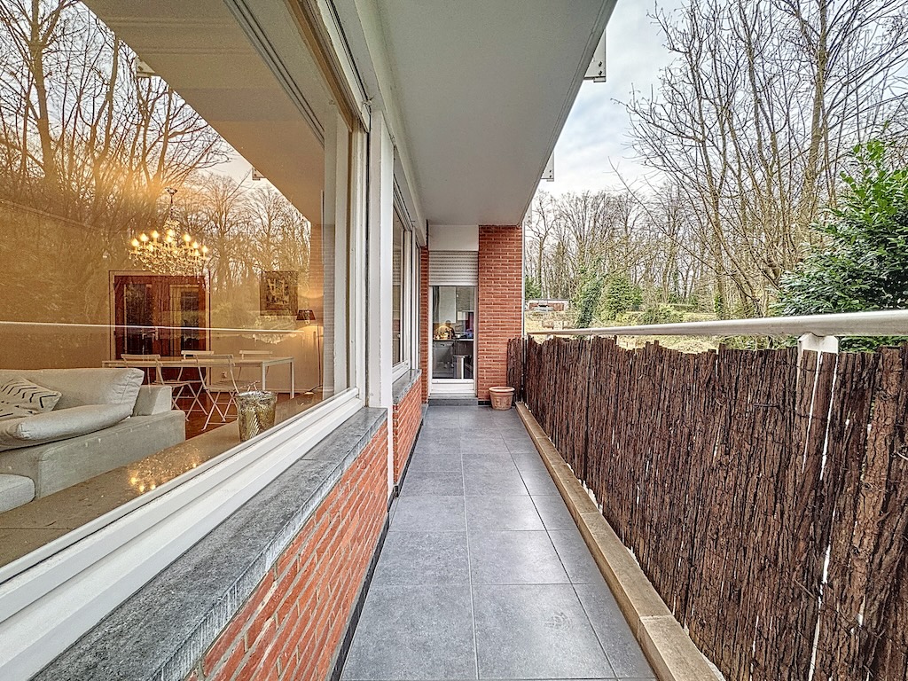 Balcon moderne avec vue sur la nature, plancher gris, clôture en bois et mur en brique chaleureuse.