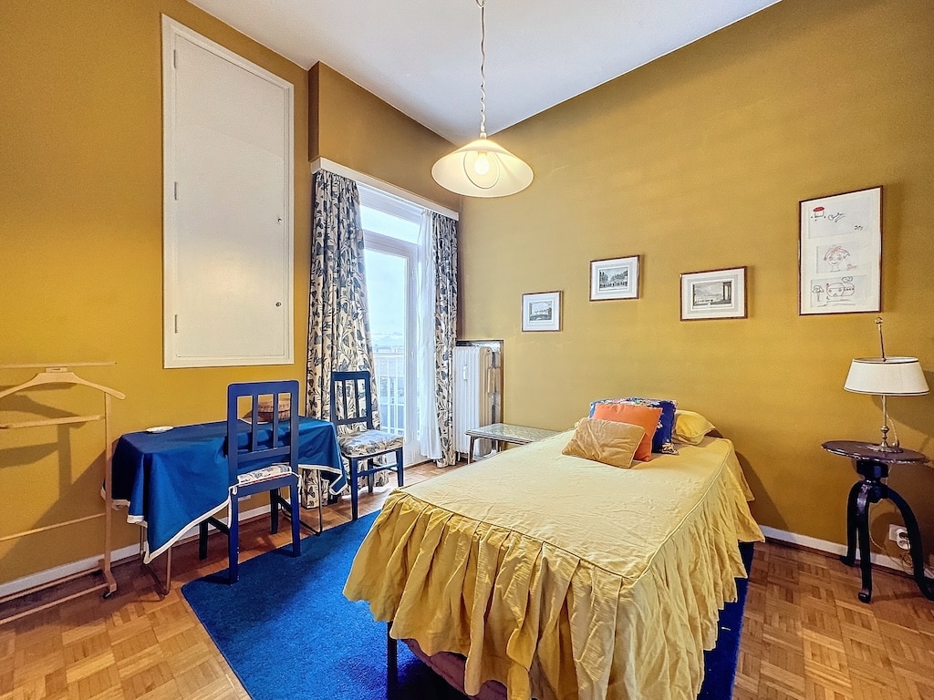 Chambre chaleureuse jaune moutarde avec lit doré, coussins colorés et espace détente élégant.