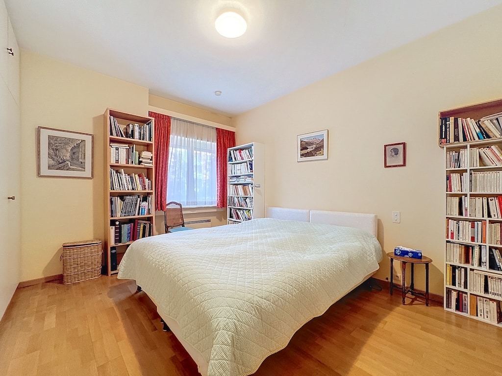 Chambre lumineuse et chaleureuse avec lit vert, étagères en bois, et décoration sobre.