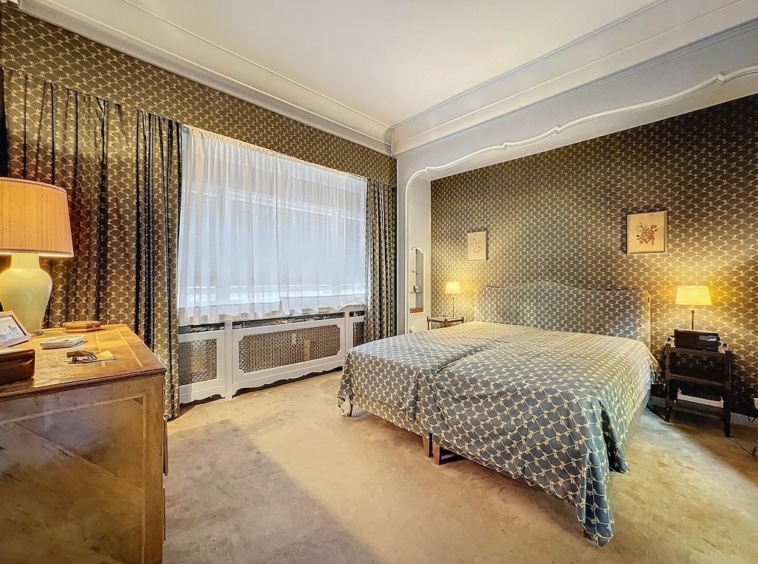 Chambre moderne élégante avec papier peint, lit cozy, luminaires vintage et ambiance apaisante.