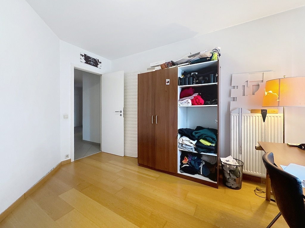 Chambre minimaliste avec bureau, rangement organisé, sol en bois clair, ambiance lumineuse et sereine.