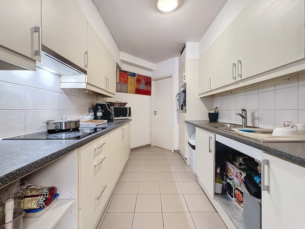 Cuisine moderne minimaliste, blanche et lumineuse avec plan en granit, décoration colorée et équipement pratique.