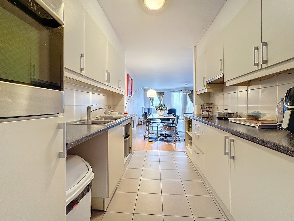 Cuisine moderne épurée avec plan de travail foncé et espace repas lumineux.