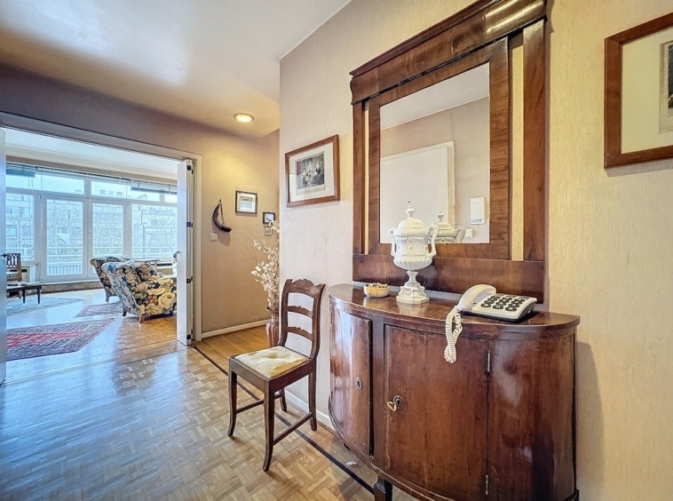 Entrée chaleureuse avec console antique, miroir, vase en porcelaine et ambiance lumineuse.