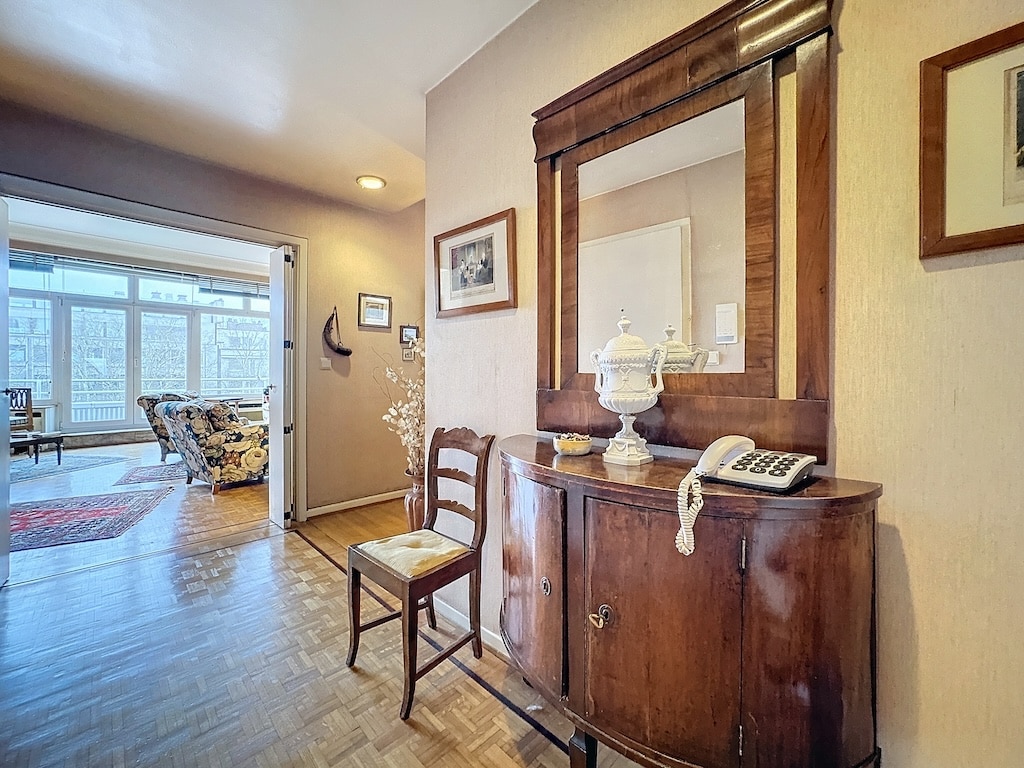 Entrée chaleureuse avec console antique, miroir, vase en porcelaine et ambiance lumineuse.