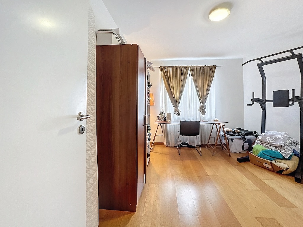 Espace multifonction moderne avec bureau, équipement de fitness, meubles en bois et ambiance chaleureuse.