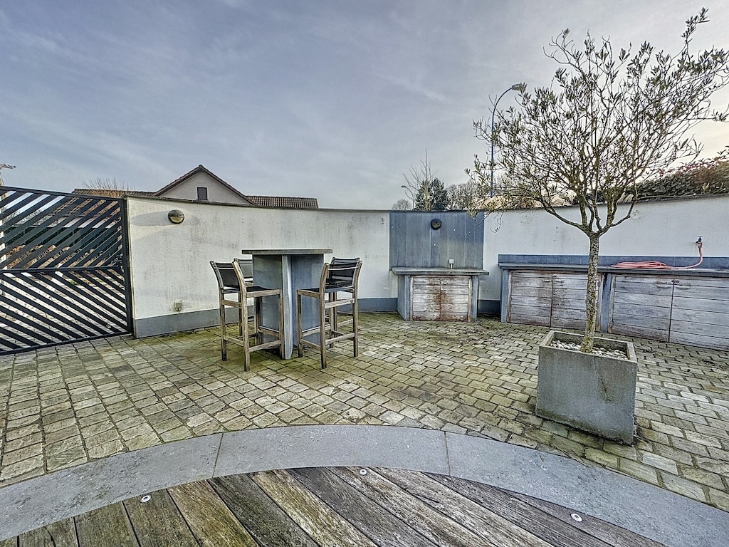 Espace extérieur moderne avec mobilier en bois, cuisine intégrée et végétation pour la détente.