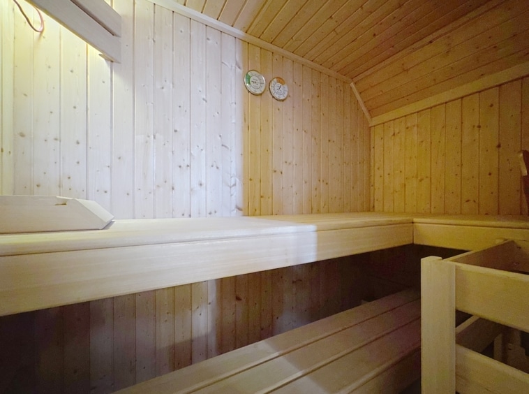 Sauna en bois clair, ambiance relaxante, bancs élégants, température et humidité contrôlées.