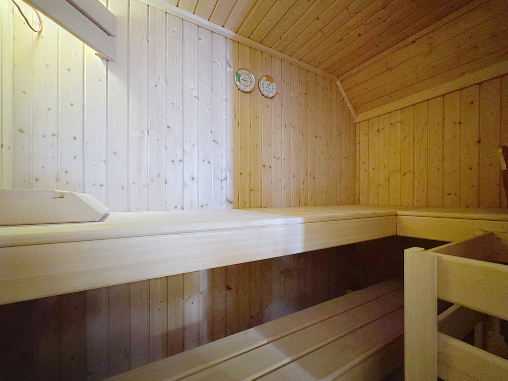 Sauna en bois clair, ambiance relaxante, bancs élégants, température et humidité contrôlées.