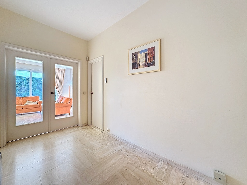 Intérieur moderne avec sol en chevrons, grandes portes vitrées, décoration épurée, ambiance lumineuse.
