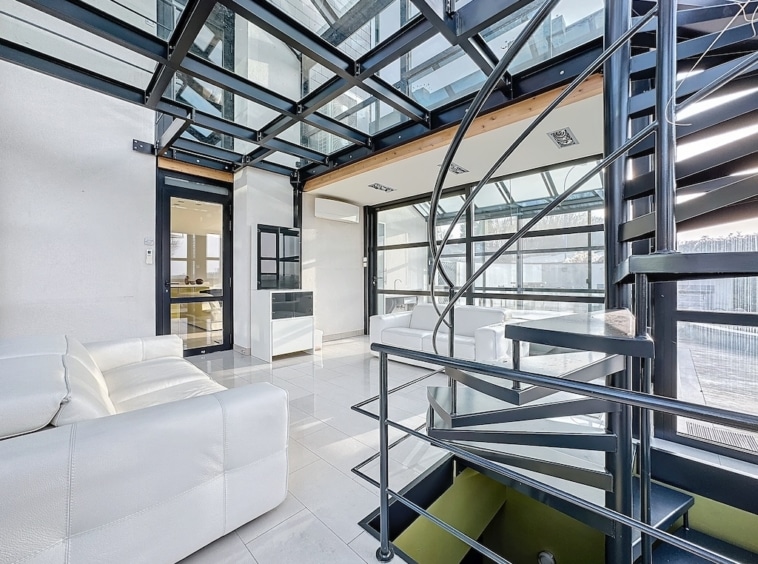 Intérieur moderne lumineux avec escalier en spirale, murs en verre et design épuré.