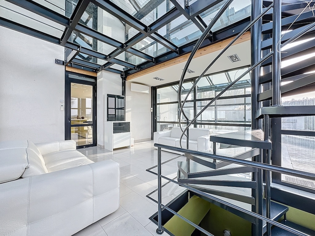Intérieur moderne lumineux avec escalier en spirale, murs en verre et design épuré.