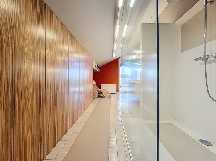 Intérieur moderne avec mur rouge, paroi en verre, décoration minimaliste et éclairage élégant.