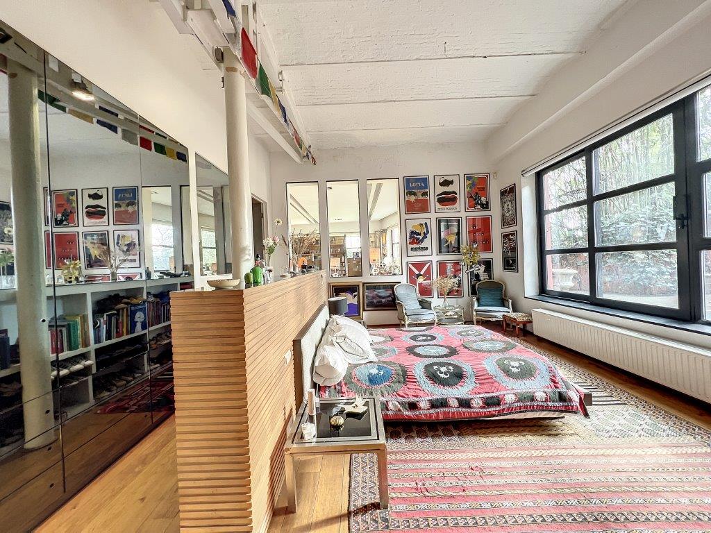 Salon moderne lumineux avec mobilier cosy, œuvres colorées et grandes fenêtres naturelles