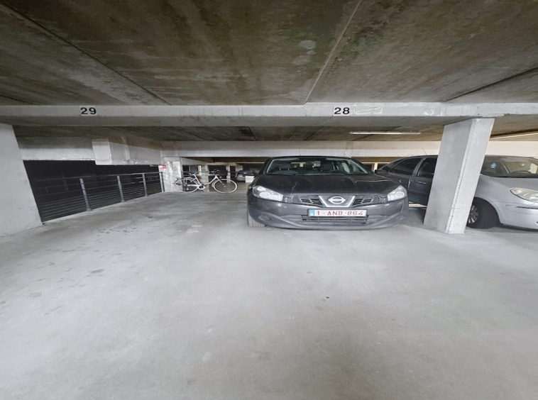 Parking souterrain minimaliste en béton avec voitures, vélo, éclairage uniforme et espace organisé.