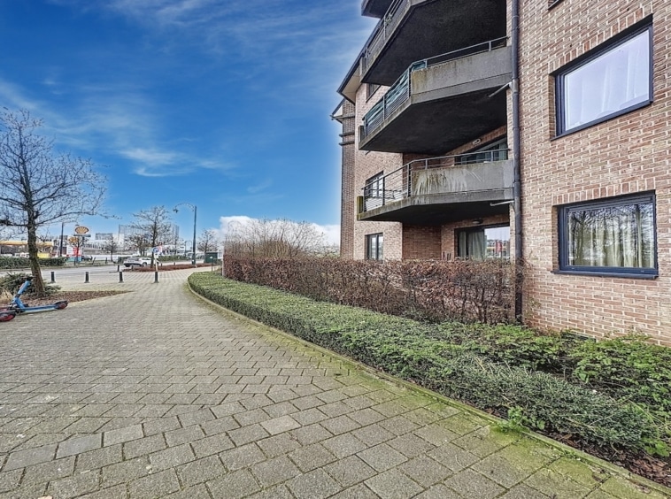 Résidence moderne en brique avec balcons, jardins urbains, allée pavée et vue panoramique.