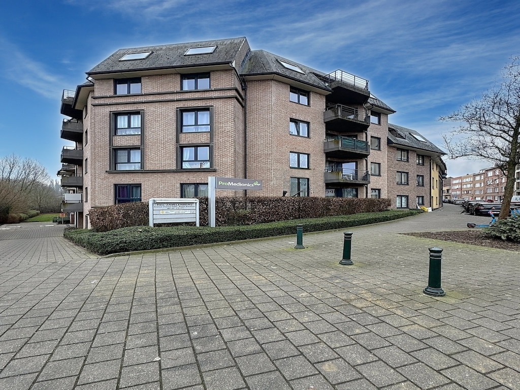 Résidence moderne en brique claire avec balcons, jardins soignés et environnement accueillant.