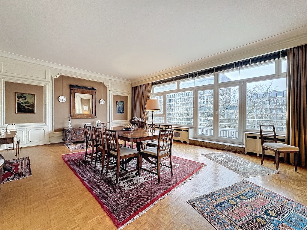 Salle à manger élégante avec grande table en bois, vue urbaine lumineuse, décoration sophistiquée.