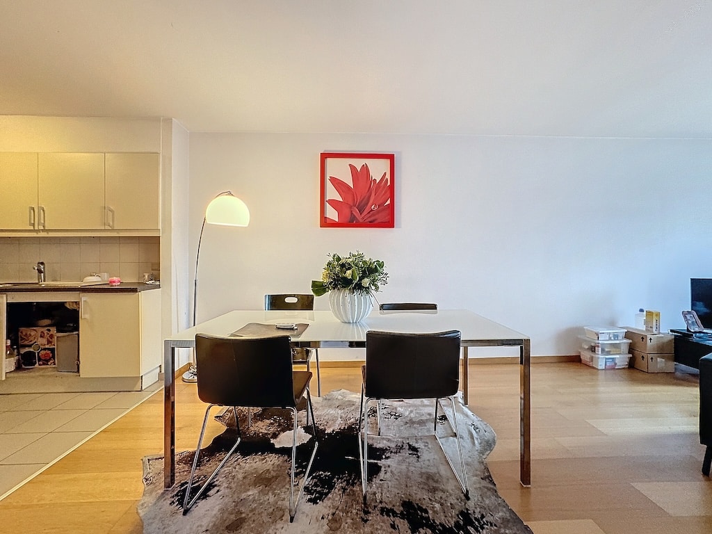 Salle à manger moderne avec artwork coloré, coin lounge et cuisine lumineuse.